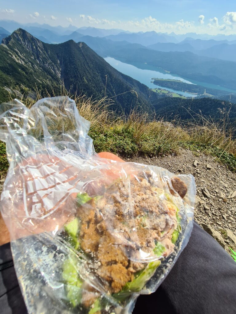 Gipfelrast auf dem Herzogstand mit zerbröseltem Sandwich in Folie, Walchensee im Hintergrund, September 2021