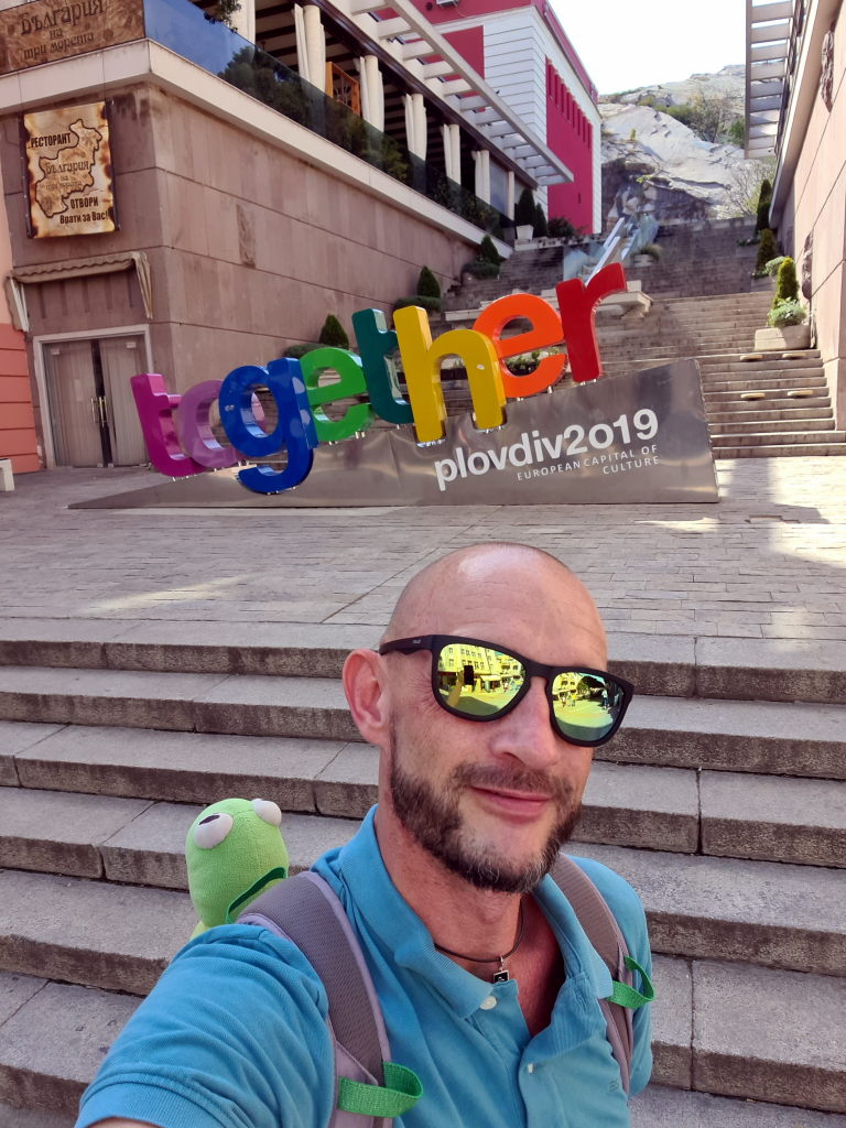 Selfie von Sebastian mit Kermit vor dem bunten Together-Schriftzug der Kulturhauptstadt Plovdiv 2019, Treppen im Hintergrund