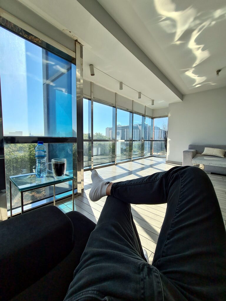 Wohnzimmer des Vitosha Panoramic Apartment Sofia mit raumhohen Fenstern, Sonnenlicht und Blick über die Stadt, September 2021