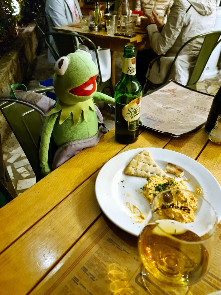 Kermit sitzt am Tisch in der Raketa Rakia Bar Sofia mit Hummus, Fladenbrot und einer Flasche Staropramen, September 2021