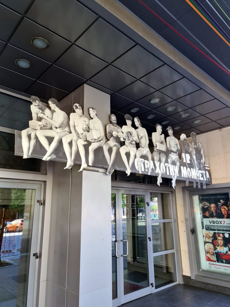 Theaterfassade in Sofia mit lebensgroßen Skulpturen sitzender Männer in Unterwäsche über dem Eingang, September 2021