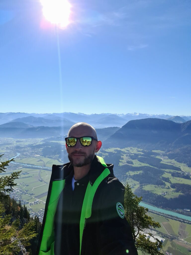 Sebastian mit Sonnenbrille am Pendling-Gipfel, Gegenlicht, Inntal und Tauern im Hintergrund