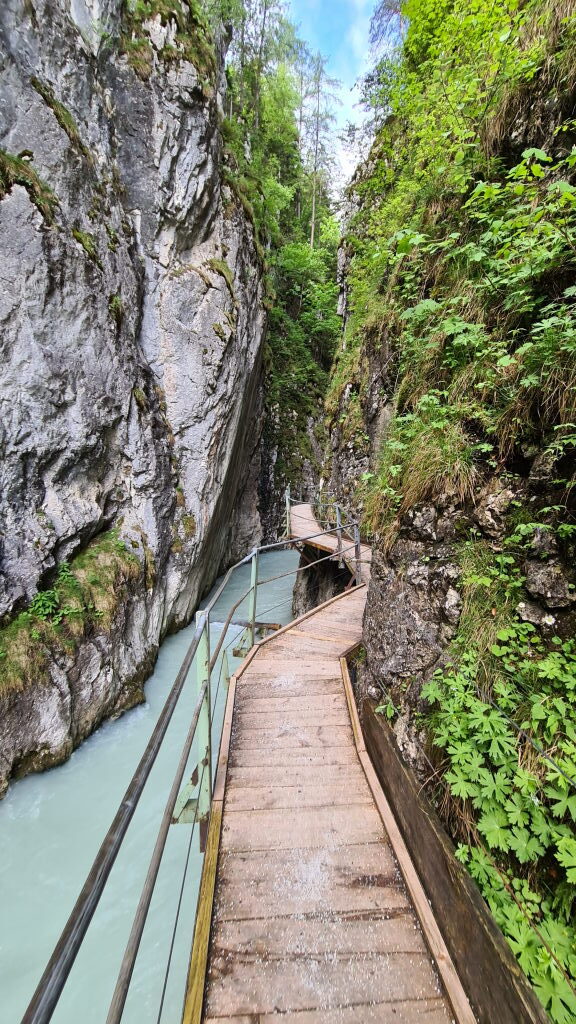 Schmaler Holzsteg durch die enge Leutaschklamm mit türkisem Wasser und senkrechten Felswänden