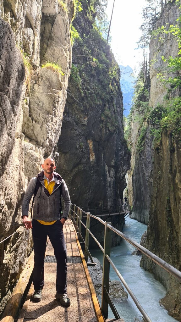 Wanderer steht auf dem Holzsteg der Leutaschklamm, dahinter die enge Schlucht mit türkisem Wasser