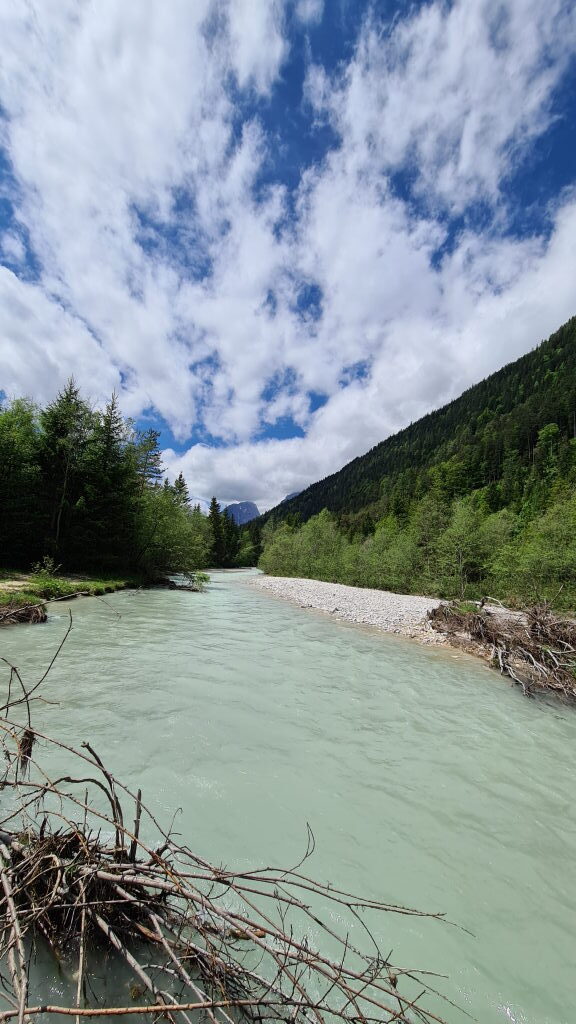 Türkis-grüne Isar mit weißen Kiesbänken und bewaldeten Bergen im Hintergrund nahe Mittenwald