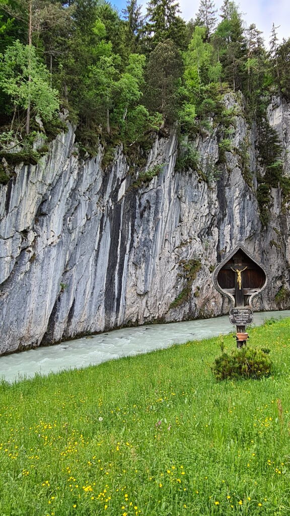 Goldenes Wegkreuz in einer Nische der senkrechten Felswand am Eingang zur Leutaschklamm