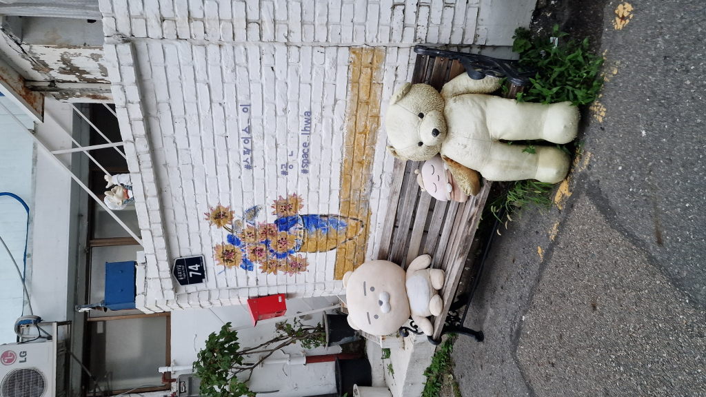 Plüschtiere auf Bank vor Wandbild Space Ihwa Seoul