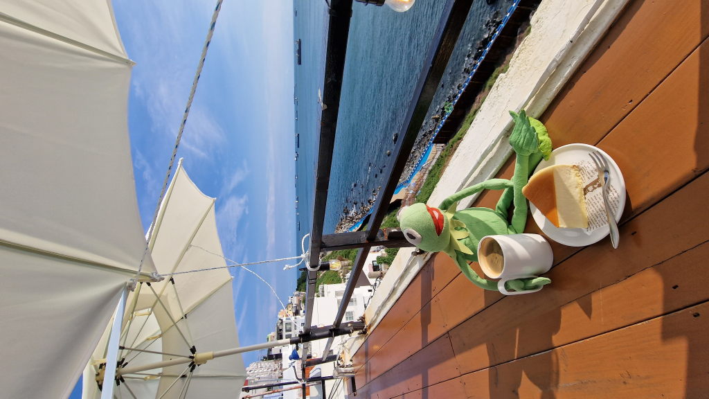 Kermit mit Kaffee und Cheesecake auf Café-Terrasse am Meer Songdo Busan