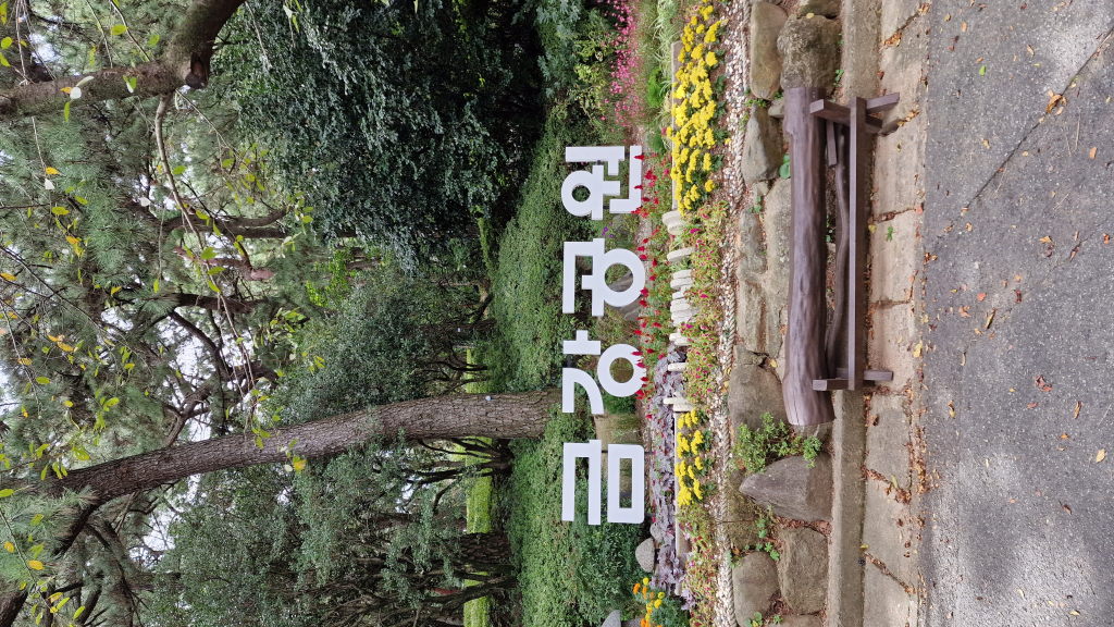 Eingangsschild Geumgang Park 금강공원 mit Bank und Blumen