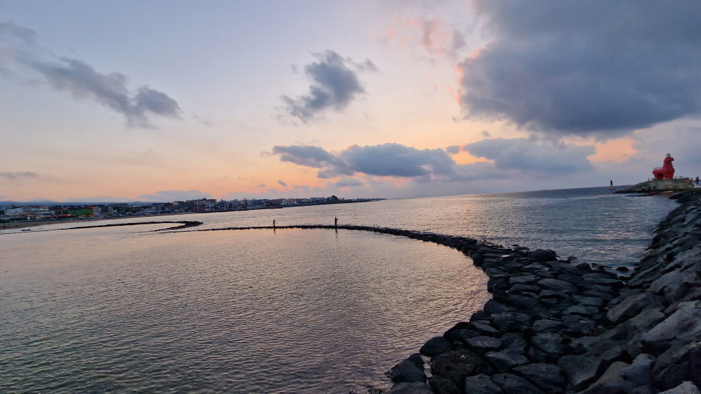 Abenddämmerung Iho Tewoo Hafen Jeju ruhiges Wasser roter Leuchtturm