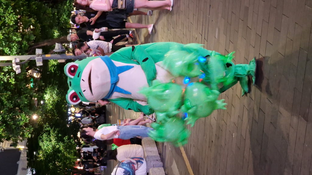 Mann im Froschkostüm mit grünen Luftballons Nguyen Hue HCMC