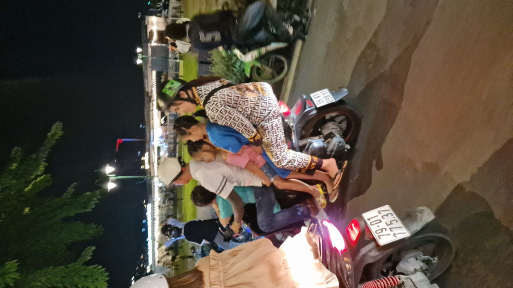 Familie mit vier Personen auf einem Motorrad HCMC bei Nacht