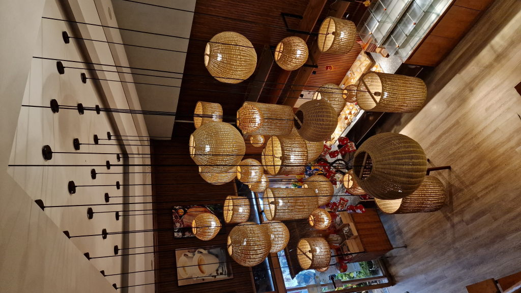 Kermit im Café Mixed Bakery unter Pflanzen und Rattanlaternen