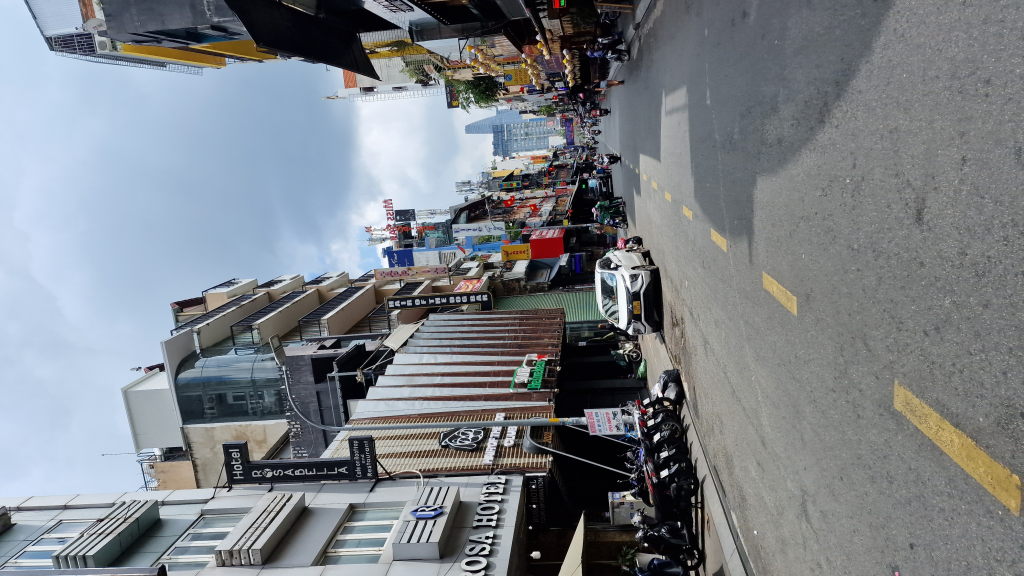 Straße in Ho-Chi-Minh-Stadt mit Hotels, Läden und Motorrädern