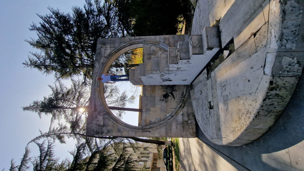 Mann steht auf einem sowjetischen Betonring-Monument in Kutaisi