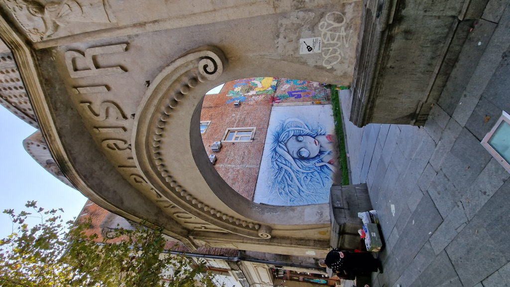 Jugendstiltorbogen Bon Plaisir mit Graffiti-Mädchen dahinter in Kutaisi