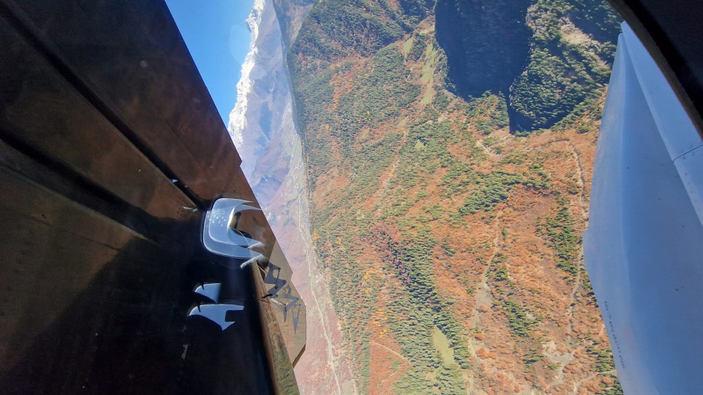 Herbstlicher Bergwald aus der Vogelperspektive mit schneebedeckten Gipfeln