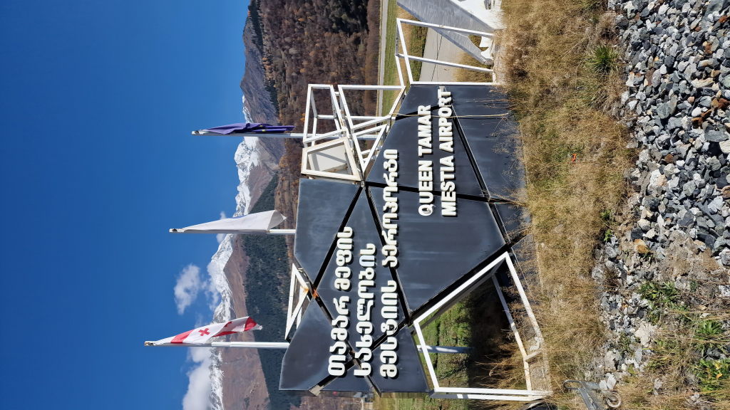 Schild Queen Tamar Mestia Airport mit schneebedeckten Kaukasus-Bergen
