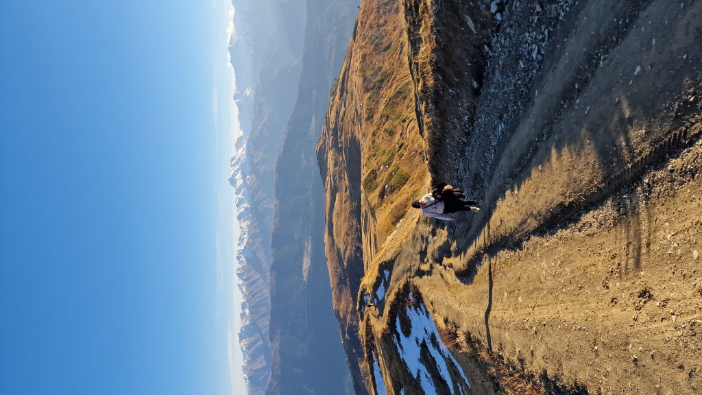 Person auf Schotterweg am Bergkamm über Mestia mit Kaukasus-Panorama