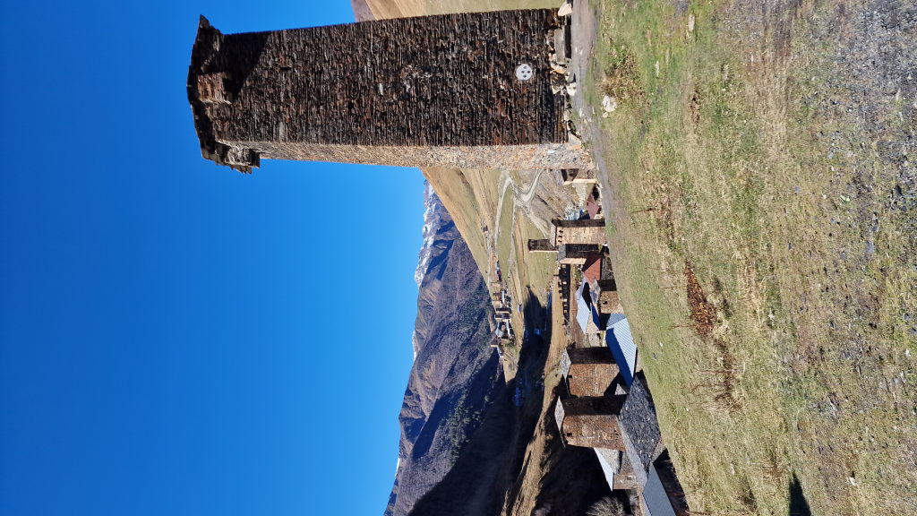 Großer mittelalterlicher Wehrturm in Ushguli mit Dorf und Bergen dahinter