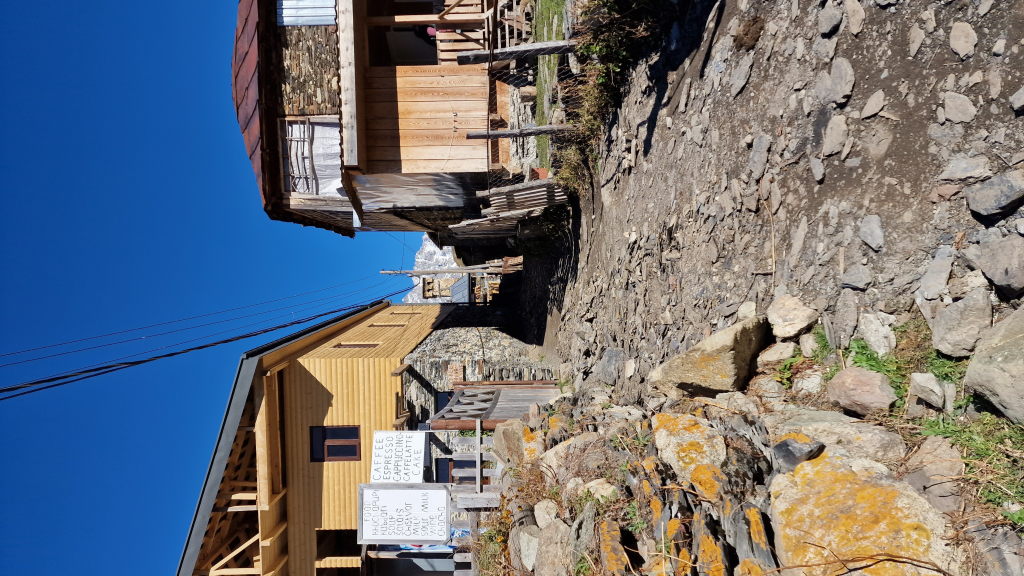 Gepflasterter Weg in Ushguli mit handgeschriebenem Kaffee-Schild