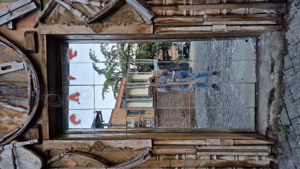 Spiegelreflexion des Fotografen in kunstvollem Holzrahmen-Eingang mit CAFE-Schrift in Tiflis