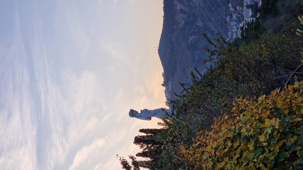 Kartlis Deda Statue in Tiflis als Silhouette vor Herbstbäumen und Hügel im Abendlicht