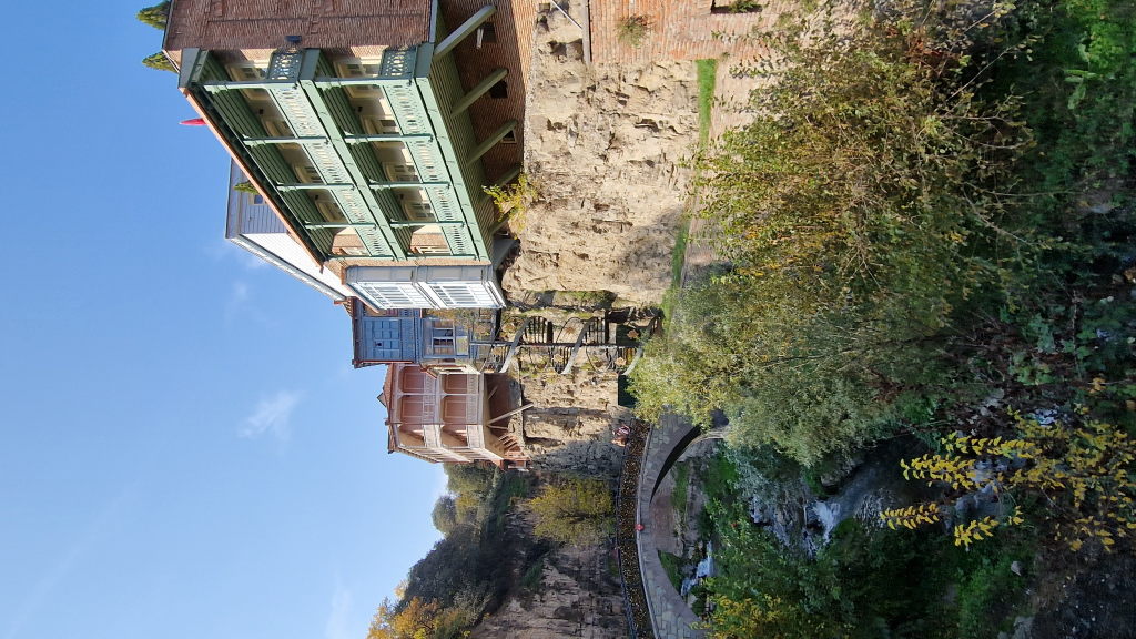 Holzhäuser mit Balkonen auf Felsen über der Leghvtakhevi-Schlucht mit Steinbrücke