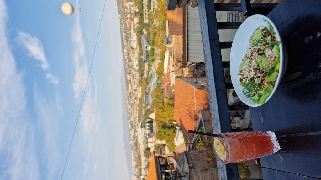 Salat und Drink auf Rooftop-Terrasse mit Tiflis-Panorama und Heißluftballon
