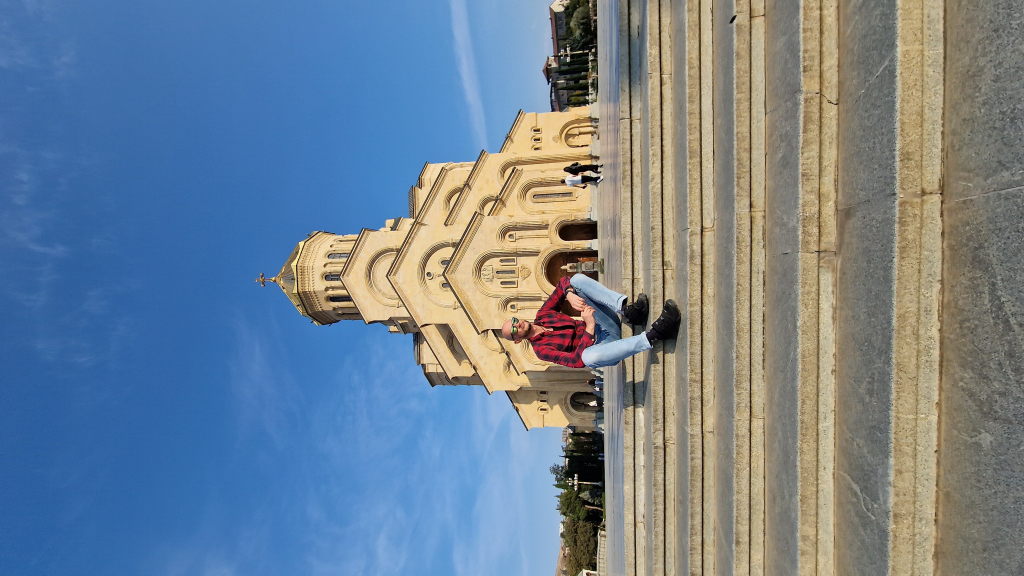 Walter sitzt auf Treppe vor der Tsminida Sameba Kathedrale in Tiflis