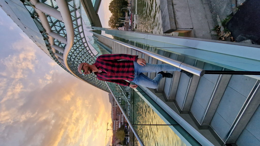 Walter auf der Friedensbrücke in Tiflis bei Sonnenuntergang mit dramatischem Wolkenhimmel
