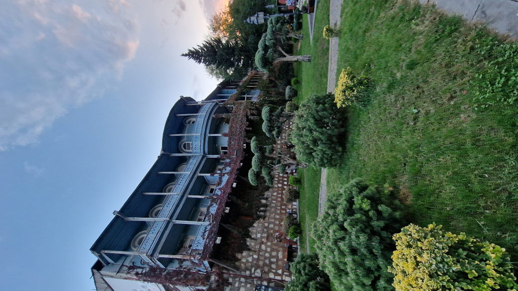 Blaues Holzgebäude mit Balkon und Rankenpflanzen im Abenddunst in Tiflis