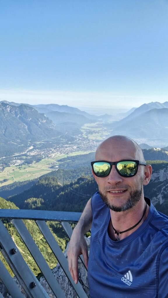 Mann mit Sonnenbrille auf der Alpspitze mit Panoramablick auf Garmisch-Partenkirchen