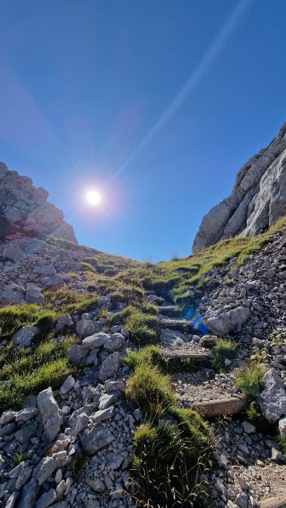 Steiler Wanderweg im Höllental mit Felsen und blauem Himmel bei Sonnenschein