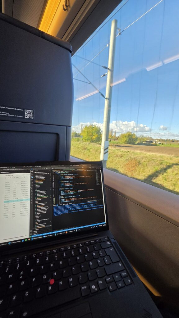 Laptop mit Code im ICE-Zug auf der Strecke München–Posen, Herbstlandschaft im Hintergrund