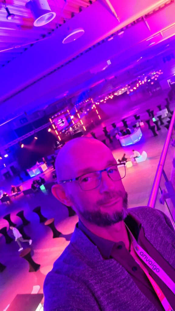 Weitwinkelblick auf die Abendveranstaltung der Directions EMEA 2025 in Posen mit pinker und lila Neonbeleuchtung, Stehtischen und Bühne