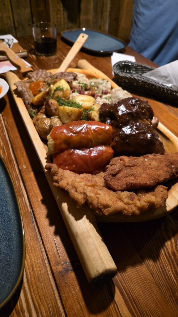 Große polnische Fleischplatte auf Holzbrett im Restaurant Wiejskie Jadło in Posen mit Schnitzel, Würstchen, Rippchen und Kartoffeln