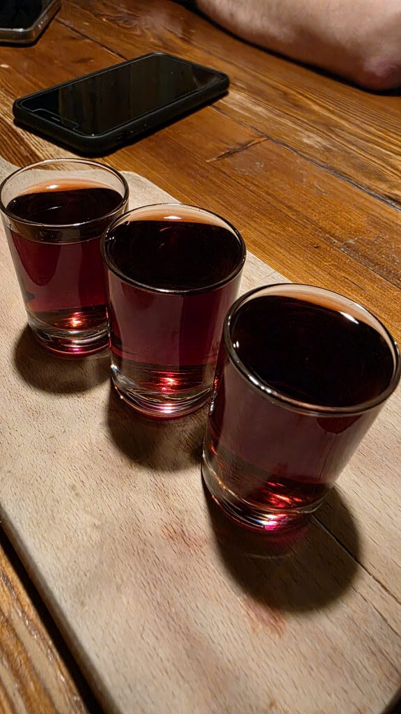 Drei Shots mit dunklem Kräuterlikör auf Holztisch im Restaurant Wiejskie Jadło in Posen